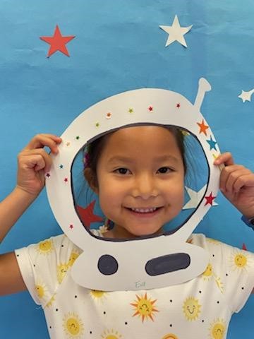 Toddler holding up space helmet crafts