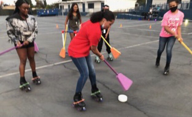 Girls on skates with paddles and a hockey puck